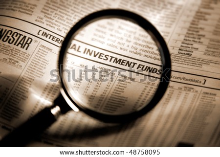 Newspaper section of the stock market index through the magnifying glass. Shallow depth of field