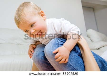 smiling young mother  with her baby having fun on her knees
