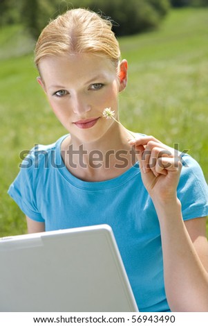 young girl with laptop and flower sitting in the grass