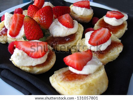 Fresh baked scones with jam and whipped cream with strawberry on top