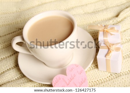 Close-up of a cup of coffee with small gift boxes and hearts