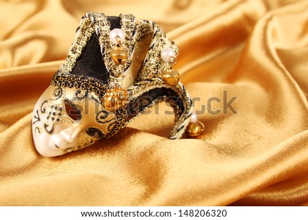 Carnival mask lying on a yellow silk