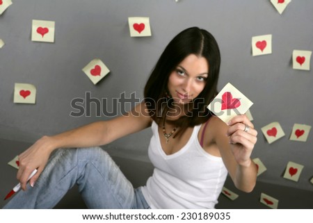 Girl with painted hearts on the wall stickers. White T-shirt and jeans on a beautiful girl in love