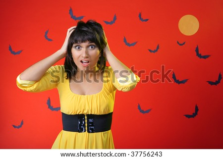 Girl in horror. Hands holding his head. Against the background of bats and the moon