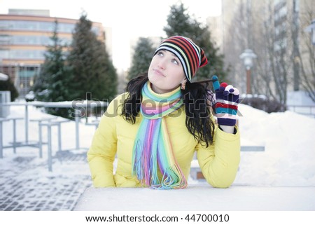 Cheerful girl winter sitting in a street cafe and twirled his finger hair