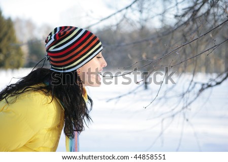 Girl in a park in the yellow jacket bites branch