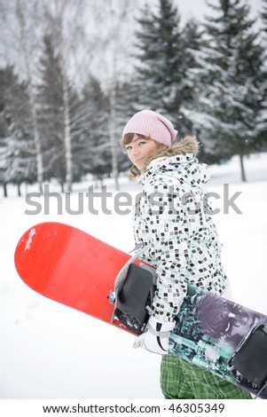 A girl in a ski suit in the mountains in winter is the red snowboard