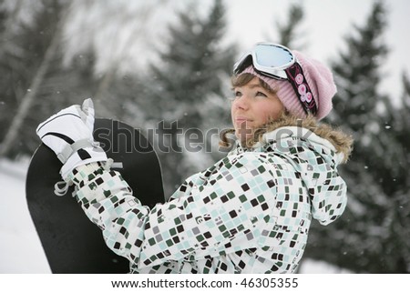 A girl in a ski suit in the mountains in winter near snowboard
