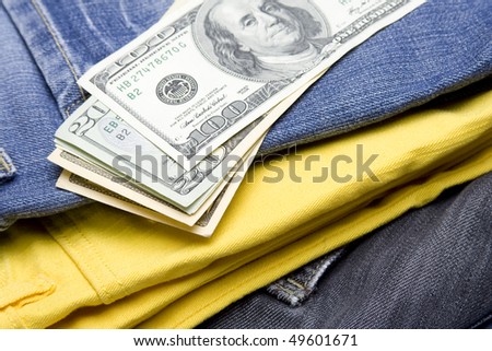Colorful collection stacked in a pile of jeans on which lies a heap Dollor U.S.