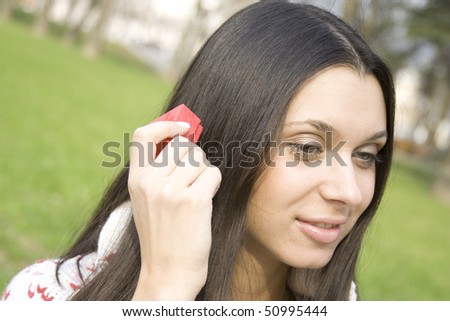 Young woman sitting on a bench in the park and treset front of the ear red gift pack