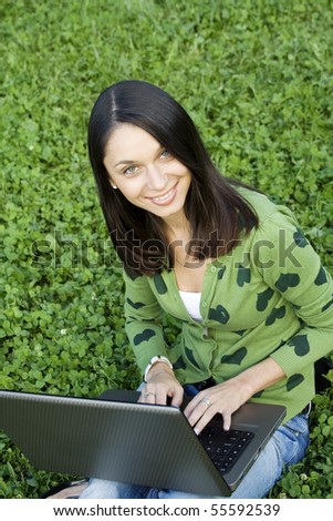 Young Caucasian woman with a laptop in the park on a green grass / meadowYoung Caucasian woman with a laptop in the park on a green grass / meadow