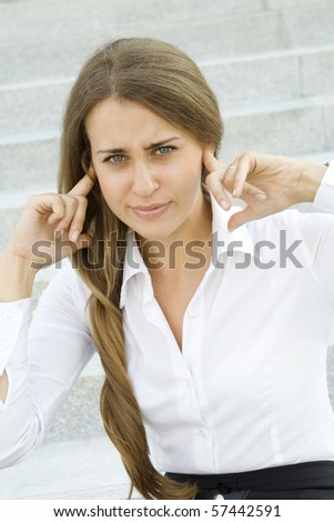 Young business woman plugs fingers in their ears