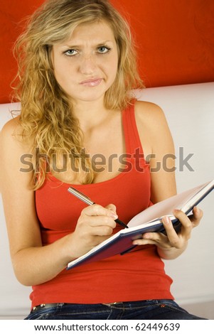 Young woman sitting on the couch and makes entries in the notebook