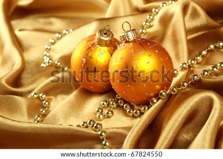 On gold fabric are gold ornaments and Christmas balls of yellow. Background