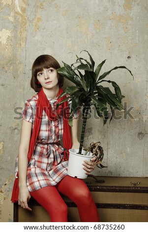 Young attractive woman sitting in the operation room in an old suitcase in the hands of plant