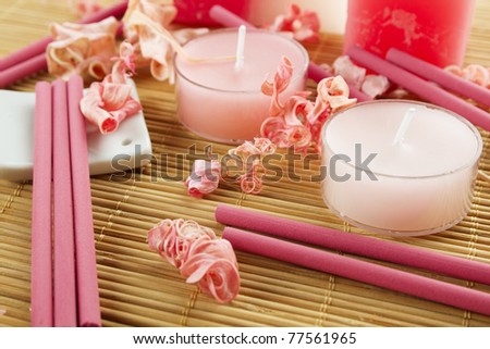 Spa treatment in bright pink and white palette, petals, candles, and arotatizirovannye sticks on a wooden bamboo rug