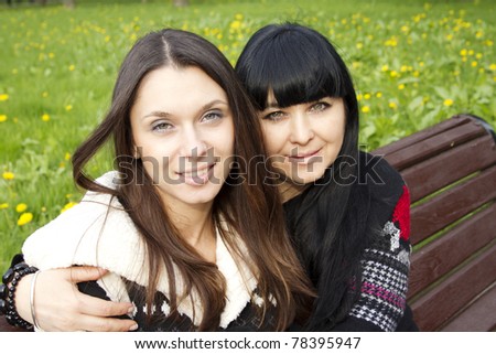 Portrait of smiling mother and teenage daughter hugging in the park happy