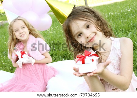 Two little girls outdoors merry, celebrate a birthday, give gifts