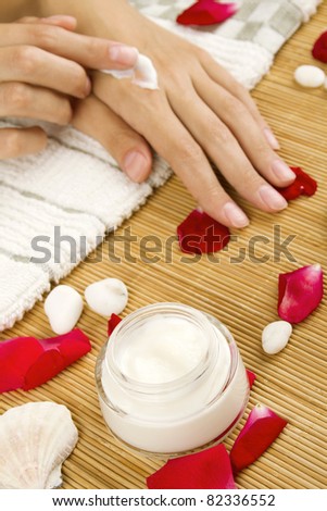 Close-up of girl lying on hand towel next to the cream, rose petals