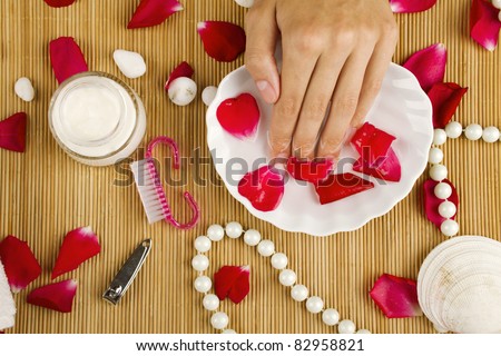Close-up of beautiful girls hands in the water next to the rose petals