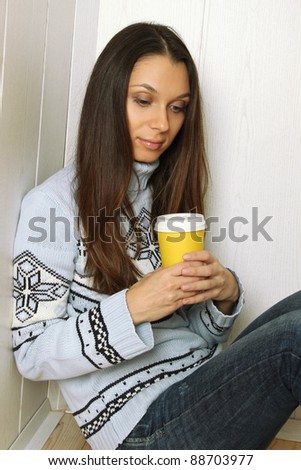 Attractive young woman at home with a paper cup of coffee drinkers