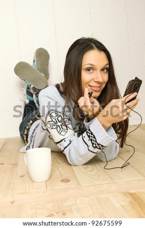 Attractive young woman lying on the floor at home listening to the radio. Listening to music