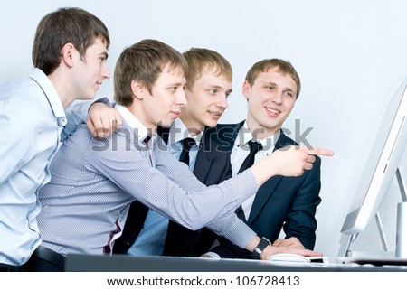 Young business man discussing project with his colleagues and pointing at computer screen