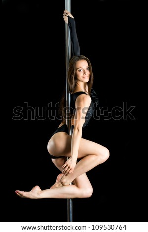 Young sexy woman exercise pole dance against a black background