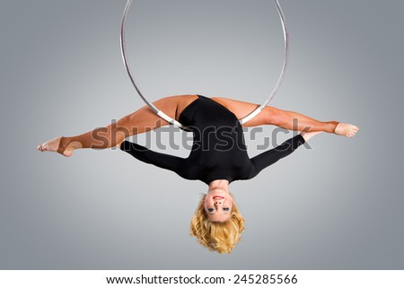 Plastic beautiful girl gymnast on acrobatic circus ring in flesh-colored suit. Aerial ring.