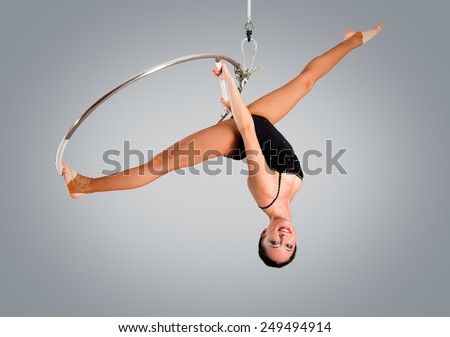 Plastic beautiful girl gymnast on acrobatic circus ring in flesh-colored suit. Aerial ring
