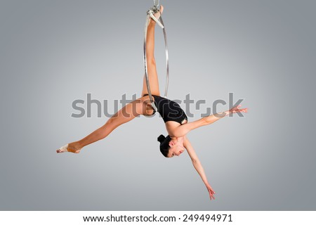 Plastic beautiful girl gymnast on acrobatic circus ring in flesh-colored suit. Aerial ring