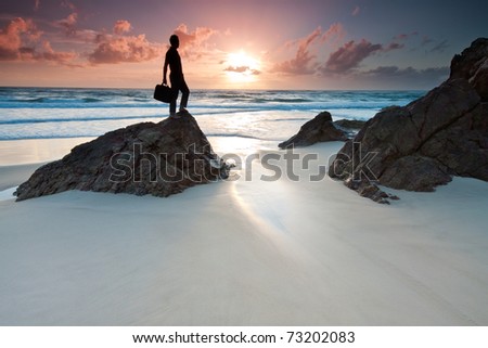 man is holding his laptop's bag when standing on top of the rock at sunrise (miami beach,queensland,australia)