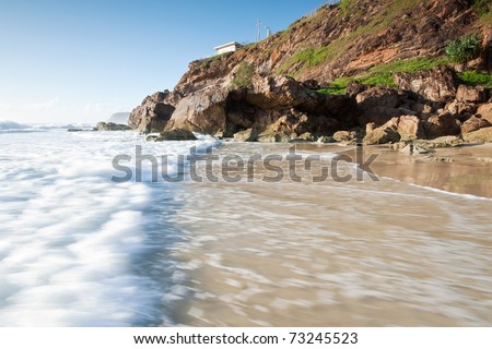 australian seascape with rushing wave in foreground and cliff face beside (miami beach,qld,australia)