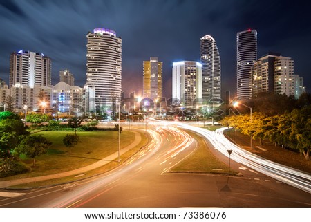 modern australian city at night with moving clouds in background and traffic car lights in foreground (broadbeach,gold coast,qld,australia)