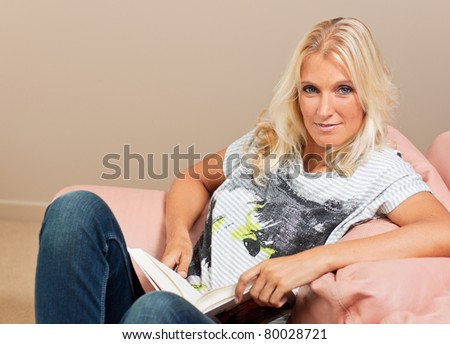 young attractive woman reads book while sitting on the sofa