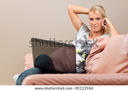 young attractive woman works on her laptop while sitting on the sofa