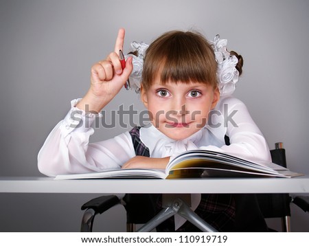 The beautiful girl with books sits at a school table