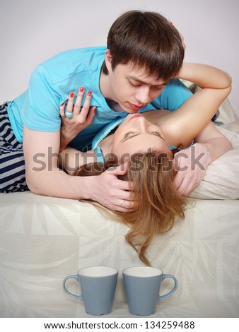 The young man kisses the girl on beds. Breakfast in a bed