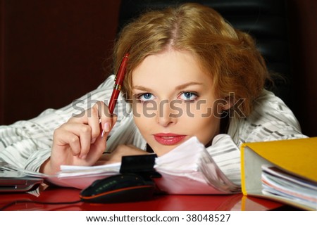 The beautiful business woman sits on a workplace and thinks