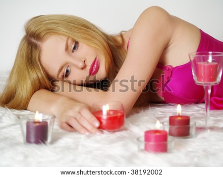 Beautiful young woman with candle, lying on fur