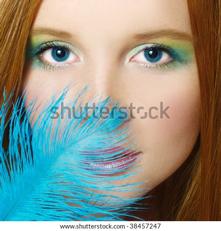 Portrait of elegant  redhead girl with blue feather