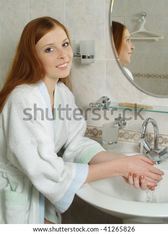 Beautiful young woman washing her face with water