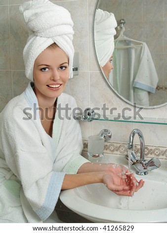 Beautiful young woman washing her face with water