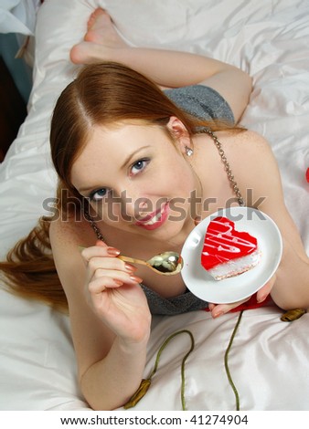 Portrait nice girl with cake lying on a bed