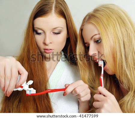 Two beautiful girls clean a teeth tooth-brush in a bathroom
