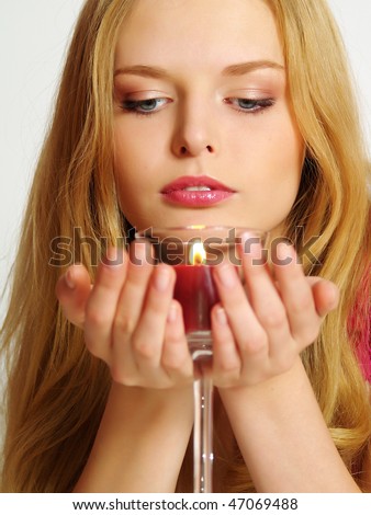 Beautiful young woman with candle in glass, look down