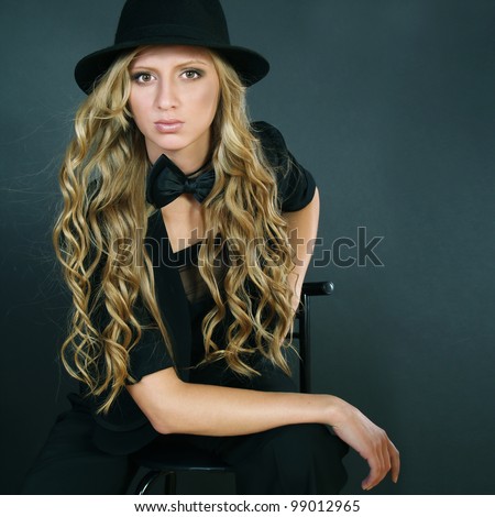The beautiful girl with long curly hair in a black hat