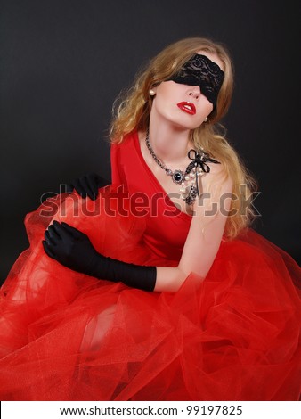 Portrait of a woman with covered eyes in red dress. Jewelry and fashion
