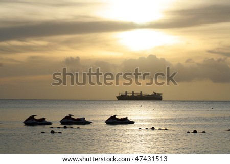 The peaceful sea with the naval ship and three motorboats floating on it.