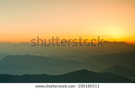 wide shot of valley with rising sun and pattern of hills